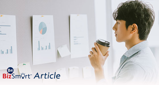 Man holding coffee cup reading info on the wall 